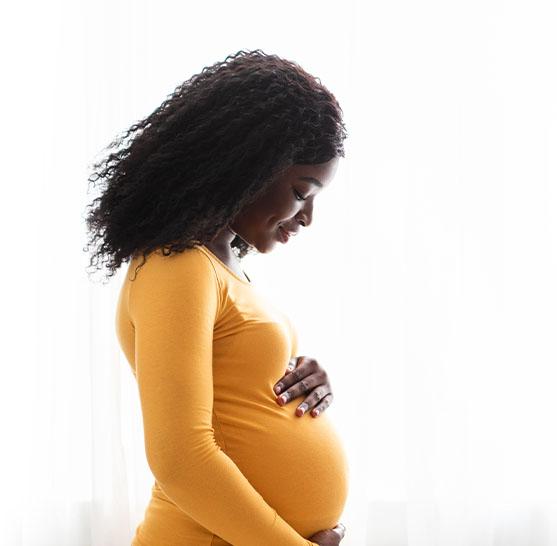 A smiling pregnant woman holding her belly